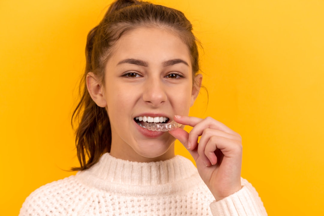 Smiling patient holding a clear Invisalign aligner tray