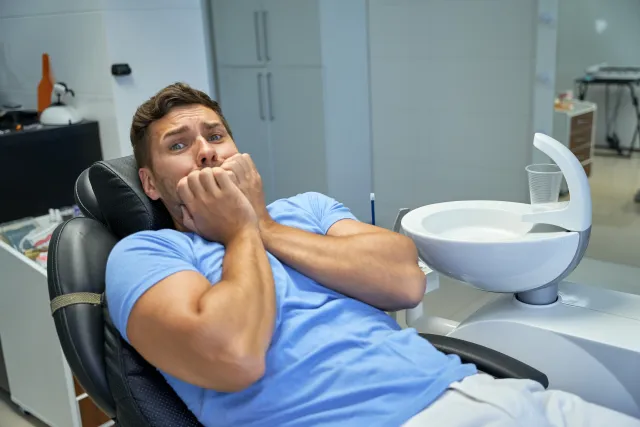 Man looking worried while sitting in a dental chair before his appointment