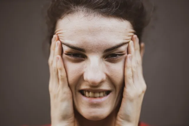 Woman holding her jaw experiencing TMJ pain and discomfort
