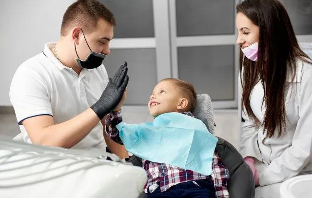 Happy child giving a high five to the dentist after a successful first dental visit