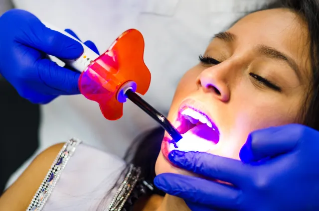 Patient receiving professional in-office teeth whitening treatment with UV light