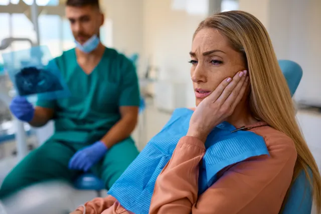 Woman experiencing a toothache at the dental clinic holding her jaw in pain